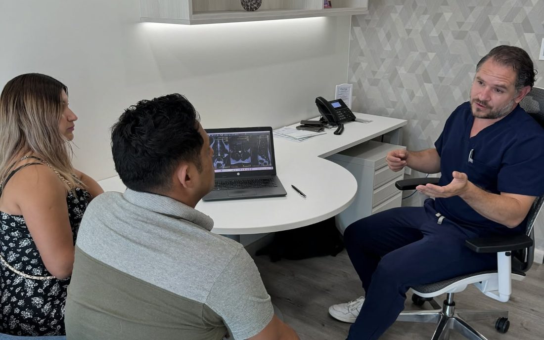 Consulta médica: el doctor explica el estudio a dos pacientes en su consultorio