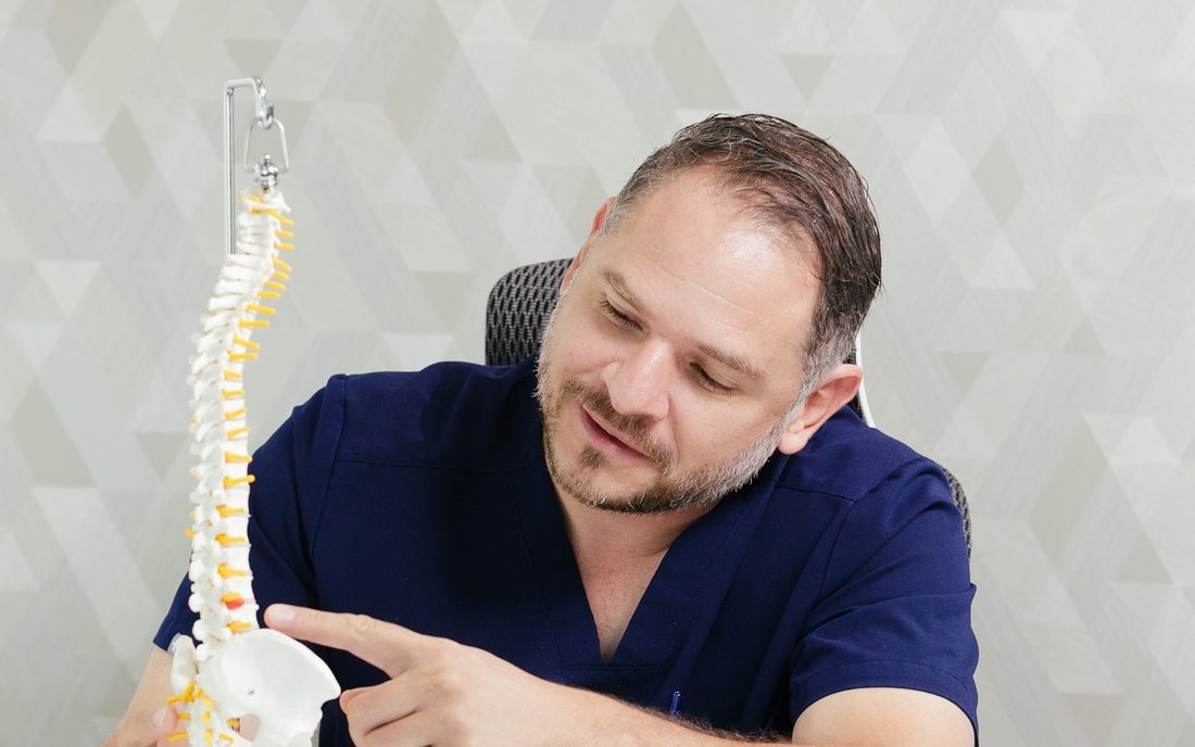 El Dr. Cisneros señalando un nivel lumbar en un modelo de columna