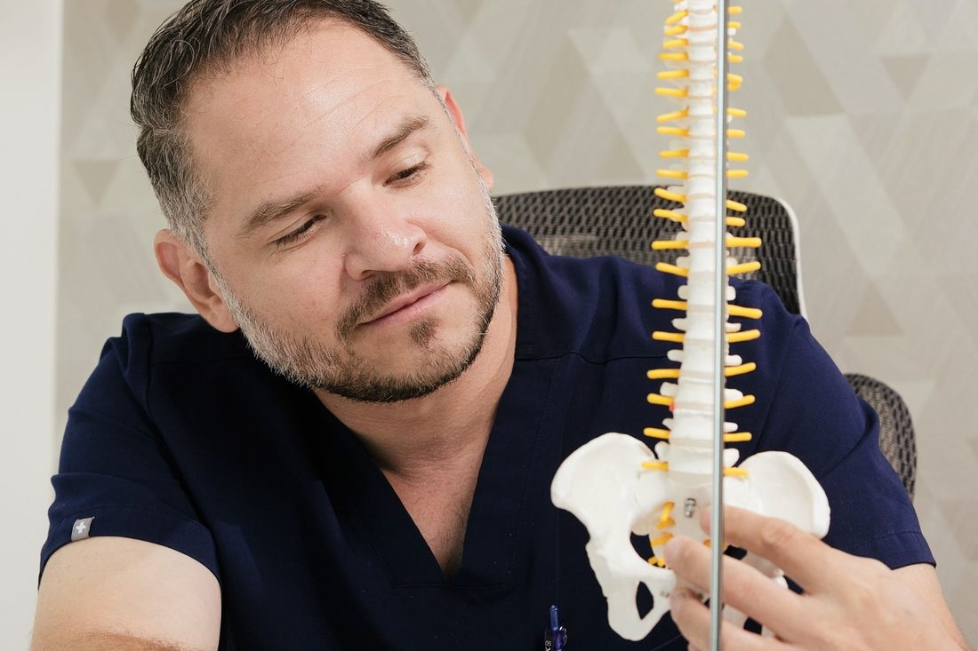 El Dr. Cisneros explica una lesión sobre un modelo anatómico de columna vertebral